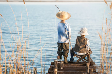 Boys fishes on a bridge on the lake