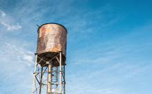 Old Rusty Water Tank On The Background Of Clear Blue Sky