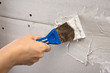 spatula with plaster in hand during plastering walls, closeup