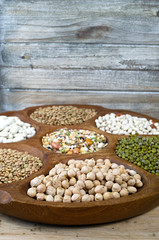 Wall Mural - Wooden bowl of various legumes on wooden background copy space