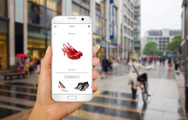Wall Mural - Online shopping with smart phone. Phone in woman hand. Buying women shoes on online store. Street walk and visiting shopping malls.