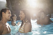 © Mint Images - A group of young men and women in the swimming pool at the end of a hot day,