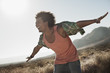 © Mint Images - A man with arms outstretched in a gesture of freedom and excitement, leaning into the breeze balancing,