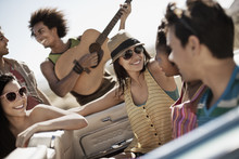 A Group Of Friends In A Pale Blue Convertible On The Open Road, Driving Across A Dry Flat Plain Surrounded By Mountains, 