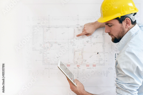 Fotografia, Obraz Bauingenieur mit Tablet vor technischer Zeichnung beim Hausbau // engineer with