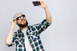 Bearded man taking selfie with smart phone in studio