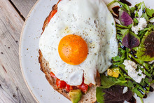 Salad With Fried Egg  On A Wood Table