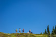 Four women hiking across a big blue sky with two dogs.