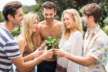 Wall Mural - Group of friends toasting beer bottles near pool