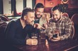 © Nejron Photo - Cheerful old friends having fun with smartphone and drinking draft beer in pub.