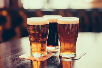 Glasses of light and dark beer on a pub background.