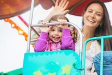 Mother And Daughter Enjoying Fun Fair Ride, Amusement Park