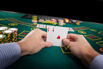 Male poker player holding the of two cards aces 