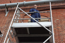 A Painter And Decorator Working From A Scaffold Tower