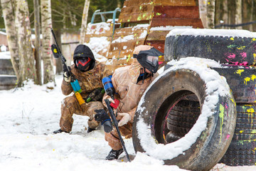 Wall Mural - Cool paintball in winter. Two shooters behind fortifications.