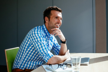 Wall Mural - Cheerful man in office sitting at the desk