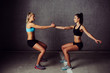 © baranq - Two attractive sportswomen stretching against a concrete background