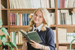 © Northern life - Smiling girl holds book near shelf in library