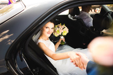 Happy Groom Helping His Beautiful Bride Out Of Wedding Car.