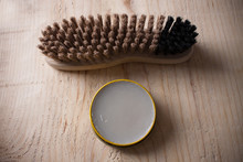 Container Of Shoe Polish And Brush On Wooden Background
