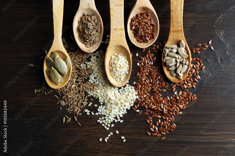 Various seeds in wooden spoons on table, closeup