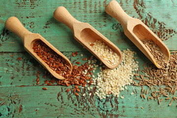 Wall Mural - Various seeds in wooden spoons on green wooden  background, closeup