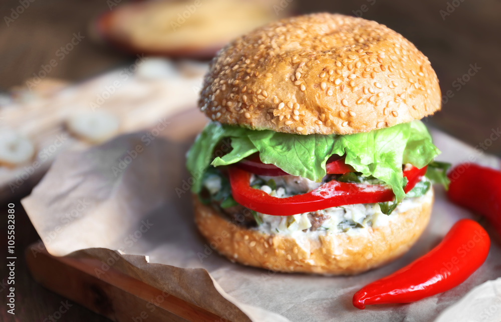 Big tasty hamburger with chili on paper, close up