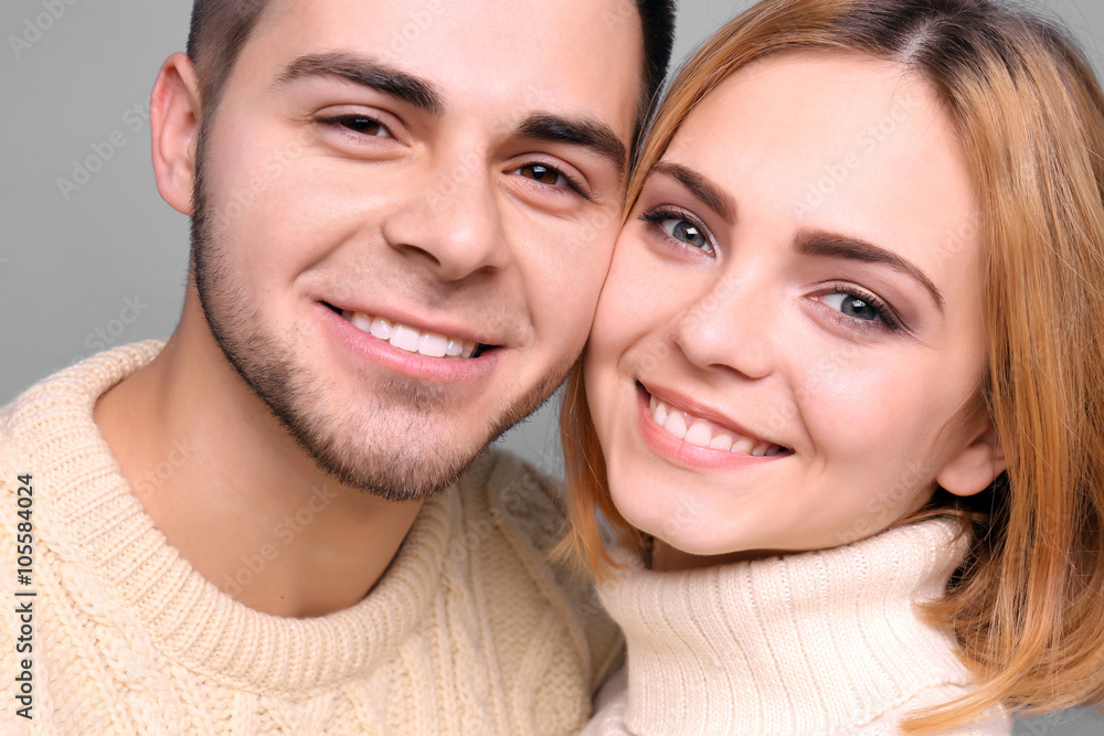 Young couple in love embracing on grey background