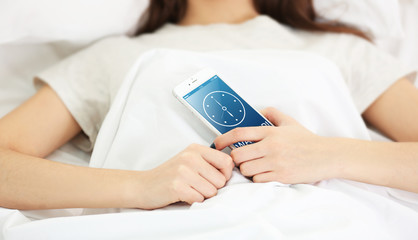 Wall Mural - Young girl lying with her phone in the bedroom.