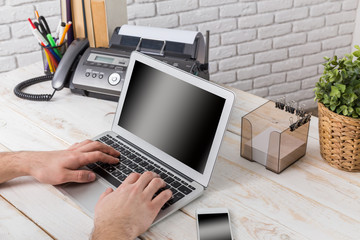 Man's hands using laptop with blank screen 