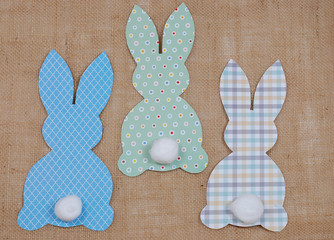 Cute craft paper cutout bunny shapes on natural background with cotton swab tails for Easter