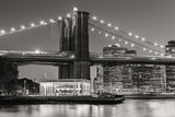 Fototapeta  - Black and White of  Brooklyn Bridge Tower at twilight with carousel and skyscrapers of Lower Manhattan. Financial District. New York City