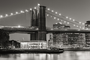 Fototapete - Black and White of  Brooklyn Bridge Tower at twilight with carousel and skyscrapers of Lower Manhattan. Financial District. New York City