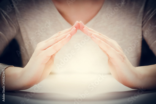 Fotografie, Obraz Light under woman's hands in gesture of protection, care.