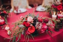 Wedding. Banquet. Marsala. In The Forest On A Wooden Porch Is Served Banquet Table With A Tablecloth Color Marsala And Vintage Chairs. On The Table Is Floral Composition And Cutlery, Glasses, Candles