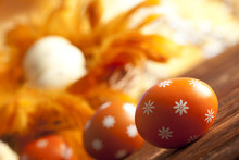 Orange Easter Eggs And Feathers On Wooden Table