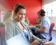 © AYAimages - Confident female designer working on a digital tablet in red creative office space