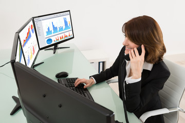 Wall Mural - Businesswoman Analyzing Graphs On Multiple Computers