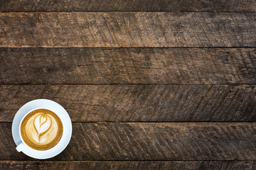 top view image of cup of latte art coffee over wooden textured t