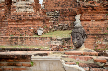 Broken buddha statue and ancient building