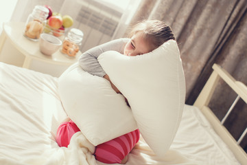 Wall Mural - Morning portrait of a little girl waking up,embracing the pillow