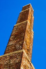 square old Industrial chimney made from red bricks against the b