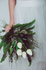 Wall Mural - Portrait of a wedding bride posing in a white dress with flowers in her hands. Beautiful wedding bouquet in hands of the bride.