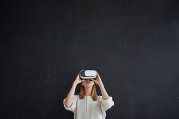 the girl in white stands on a black background in the virtual reality helmet