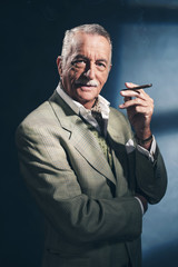 Wall Mural - Cigar smoking retro 1940 senior businessman. Studio shot.