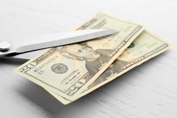 Poster - Scissors cuts dollar banknote on table