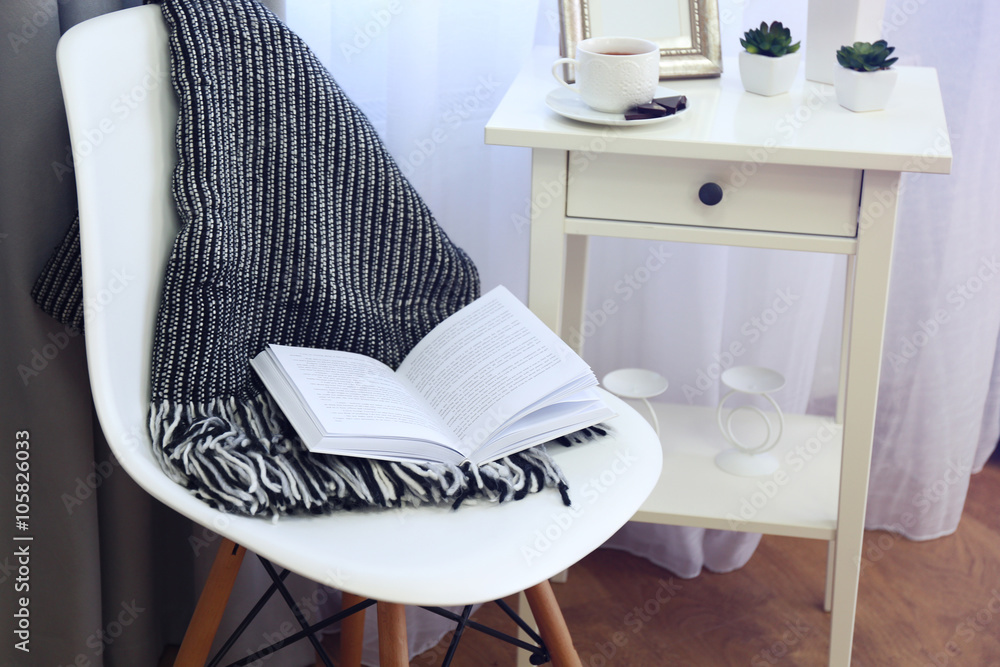 A soft blanket and a book on the chair. Peace and comfort concept