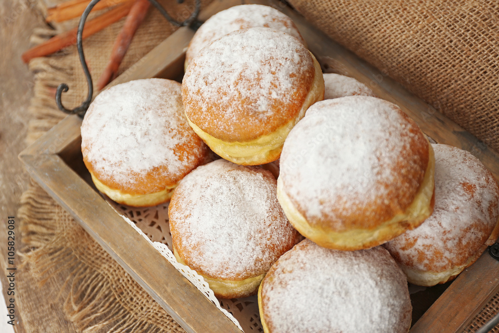 Delicious sugary donuts in wooden tray closeup