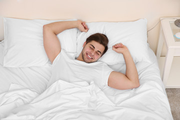 Wall Mural - Young man stretching on bed in bedroom