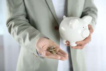 Wall Mural - Man in suit holding piggy bank and coins closeup